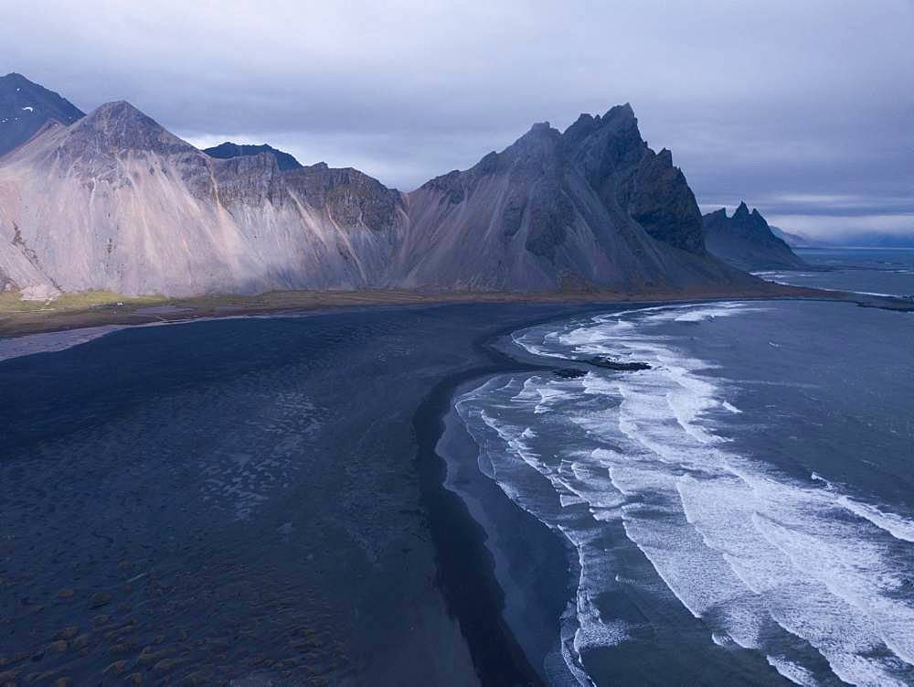 Aerial view, black lava edge with sea surf with mountain Vestrahorn, Cape Stokksnes, bay Hornvik, southeast Iceland, Iceland, Europe