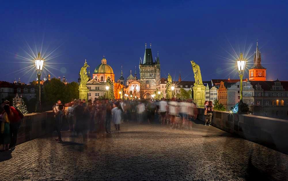 Karluv most, people on the Charles Bridge at dusk, in the back dome of the church Kreuzherrenkirche with old town bridge tower, Prague, Bohemia, Czech Republic, Europe