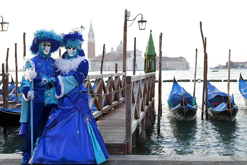 Blue couple standing in front of gondolas, carnival in Venice, church San Giorgio Maggiore in the back, Venice, Italy, Europe