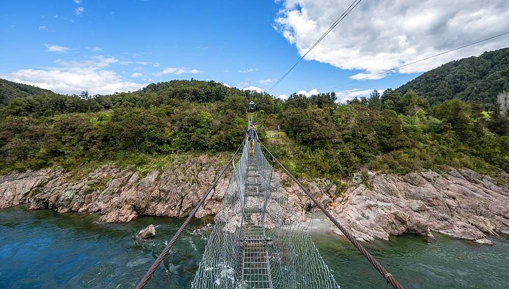 Young man on suspension bridge over Buller River, Buller Gorge Swing Bridge, Inangahua, West Coast, South Island, New Zealand, Oceania