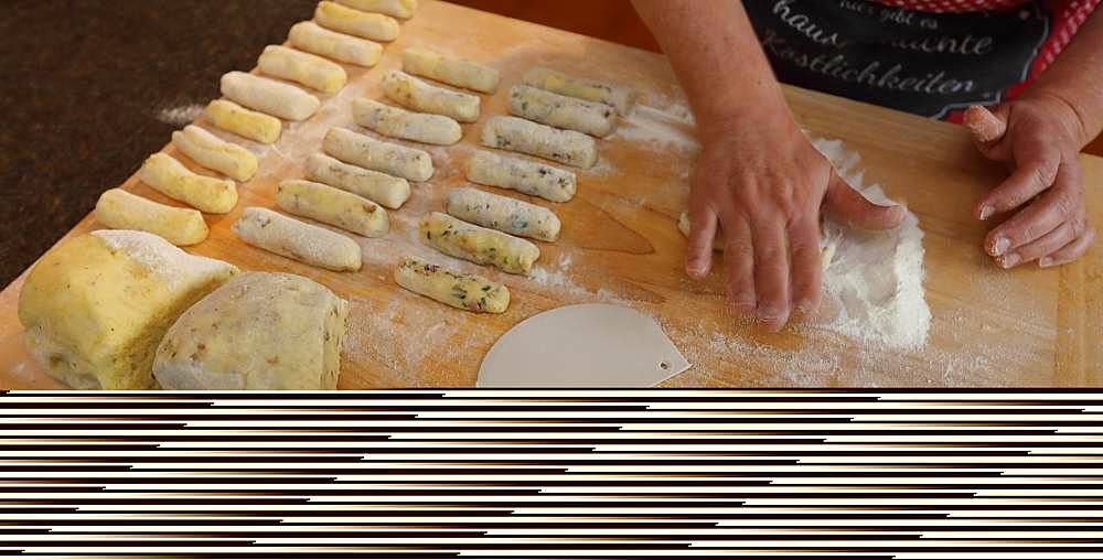 Hands rolling potato dough on wooden board with flour, Bavaria, Germany, Europe