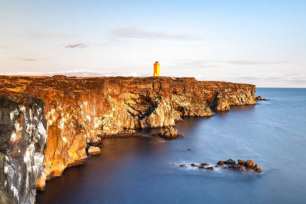 Orange lighthouse of Oendverdarnes stands at cliff coast, rocky coast of lava rock, long time exposure, Oendveroarnes, Snaefellsjoekull National Park, Snaefellsnes Peninsula, Snaefellsnes, Vesturland, Iceland, Europe