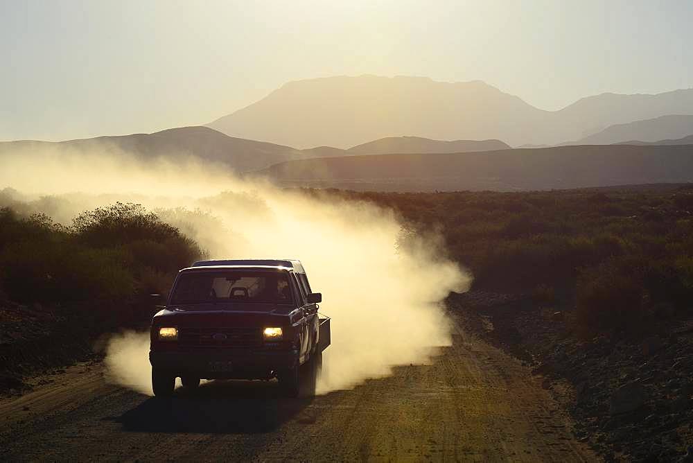 All-terrain vehicle with dust cloud on track through volcanic lunar landscape, Reserva La Payunia, Mendoza Province, Argentina, South America