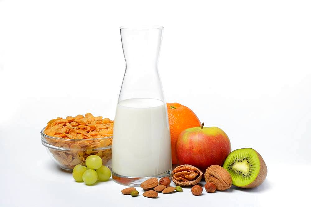 A carafe with milk, bowl with cornflakes, fruits and nuts, Germany, Europe