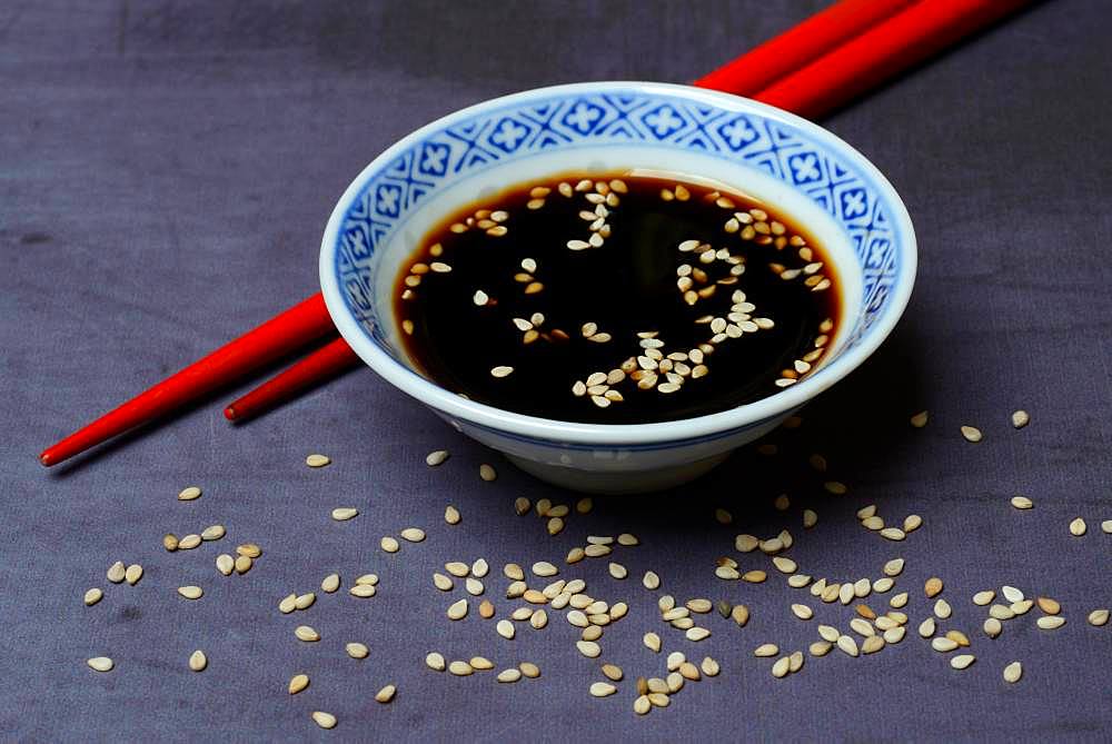 Sesame seeds with soy sauce in small bowls and red chopsticks, Germany, Europe