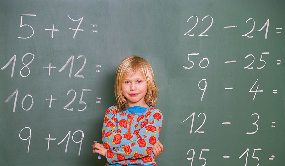 Schoolgirl stands in front of the blackboard in the classroom and calculates, Austria, Europe