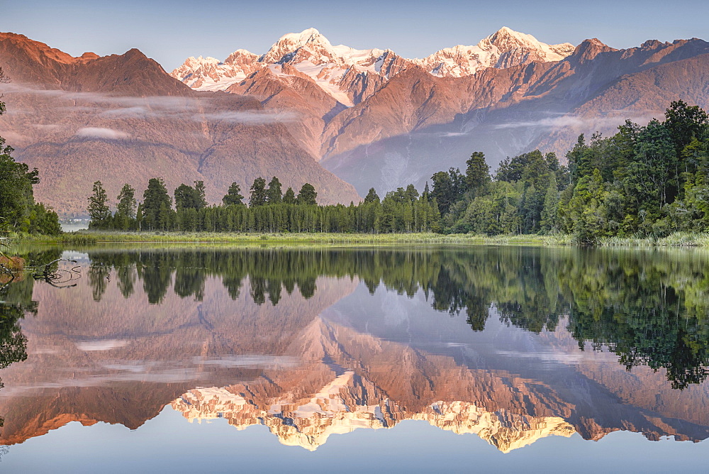 Snowy mountain peaks of Mount Cook and Mount Tasman reflected in Lake Matheson in the evening light, Westland National Park, Fox Glacier, Whataroa, West Coast, New Zealand, Oceania