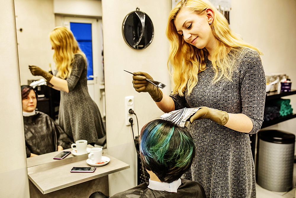 Hairdresser in a hairdressing salon dying strands of hair with aluminium foil, Cologne, North Rhine-Westphalia, Germany, Europe