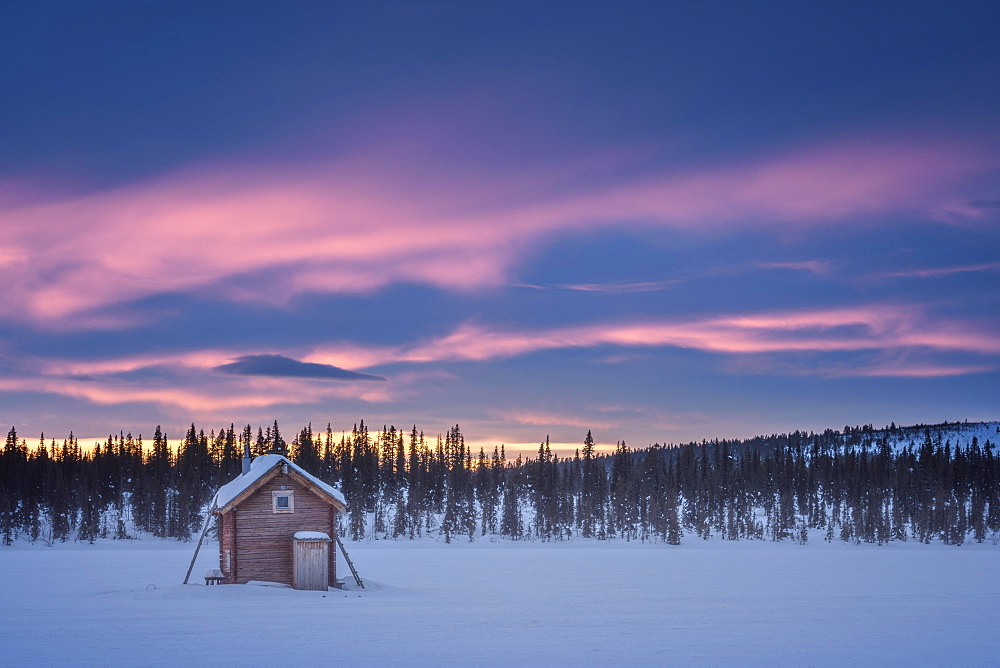 Small wooden hut on a wide snow-covered plain at extremely low temperatures at dawn, Skaulo, Norrbottens laen, Sweden, Europe