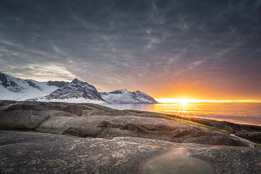 Rocky beach of Tungeneset, snow-covered mountain peaks in the warm sunlight above the sea, stone fjords, Senja Island, Skaland, Troms, Norway, Europe