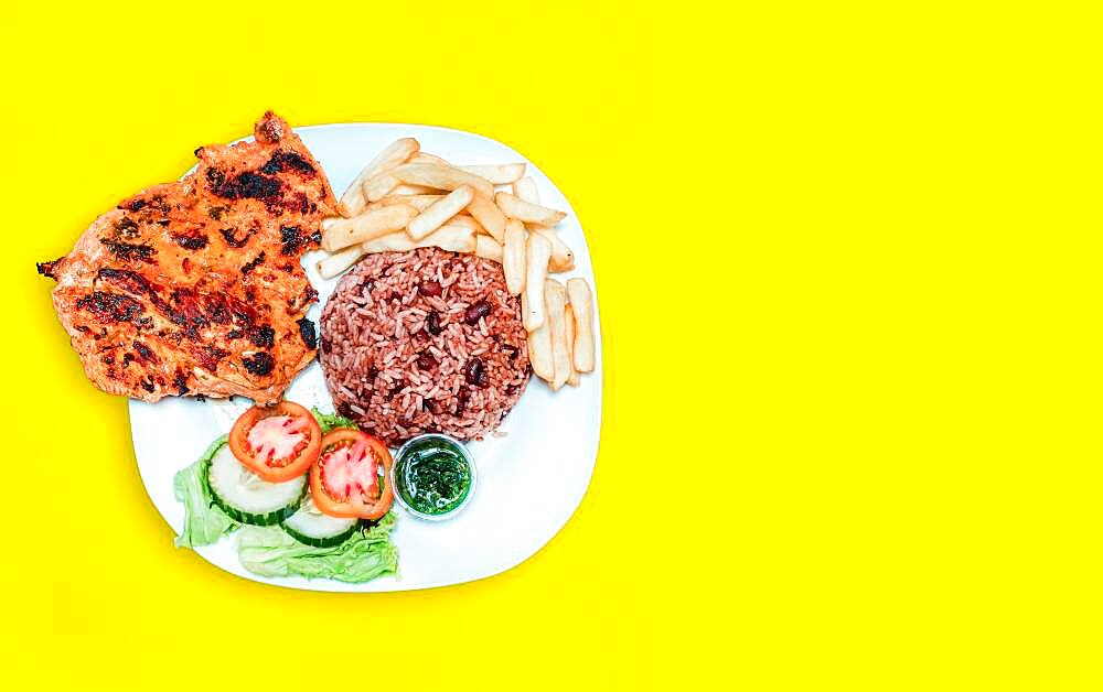 Nicaraguan food plate with yellow background with copy space, chicken plate with potatoes and salad with yellow background