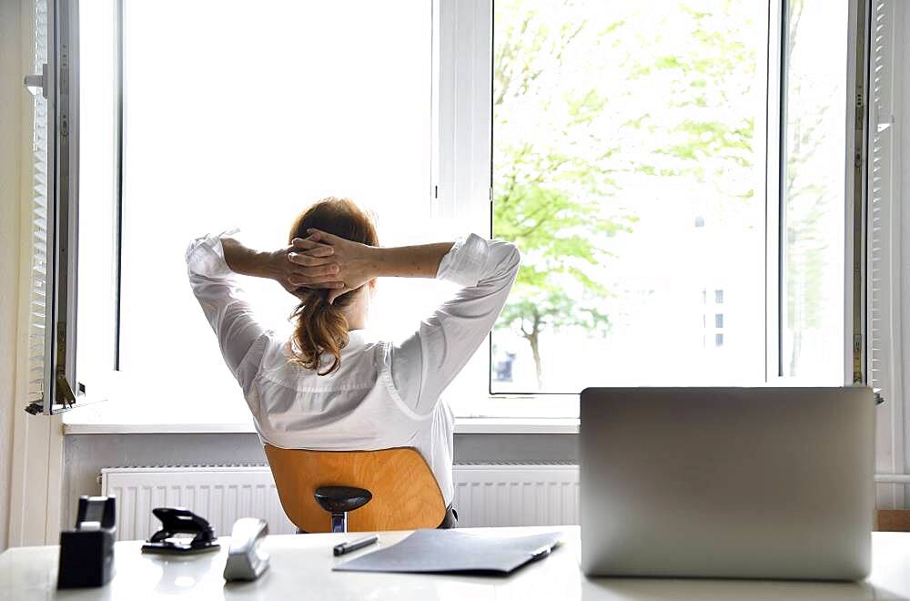 Woman sitting in the office with the window open, Germany, Europe