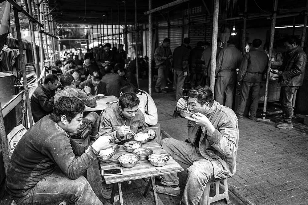 Worker having lunch at a stall in a market in the center of Chongqing, from his wages he can only buy the cheap pieces of meat, Chongqing, China, Asia