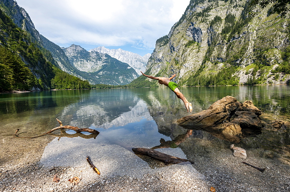 Young man jumps into lake, bathes in mountain lake, mountains are reflected in Obersee, behind Watzmann, salet at Koenigssee, Berchtesgaden National Park, Berchtesgadener Land, Upper Bavaria, Bavaria, Germany, Europe