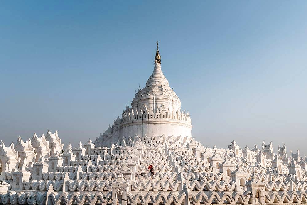 Buddhist monk stands with red umbrella in front of Hsinbyume Pagoda, Mingun, Myanmar, Asia