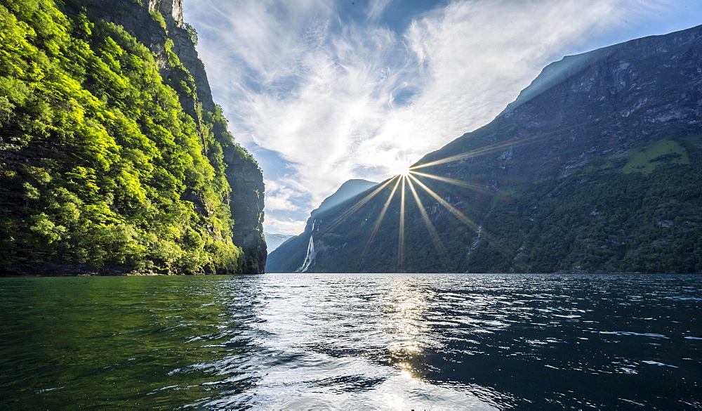 Sun and mountains reflected in the Geirangerfjord, near Geiranger, More og Romsdal, Norway, Europe