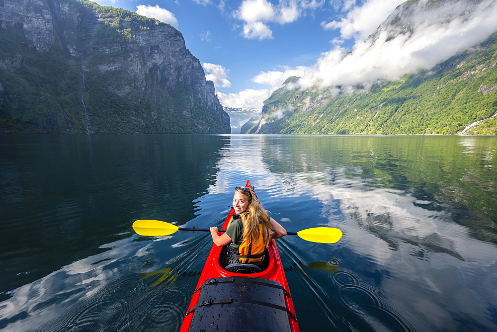 Young woman paddling in a kayak, Geirangerfjord, near Geiranger, Norway, Europe