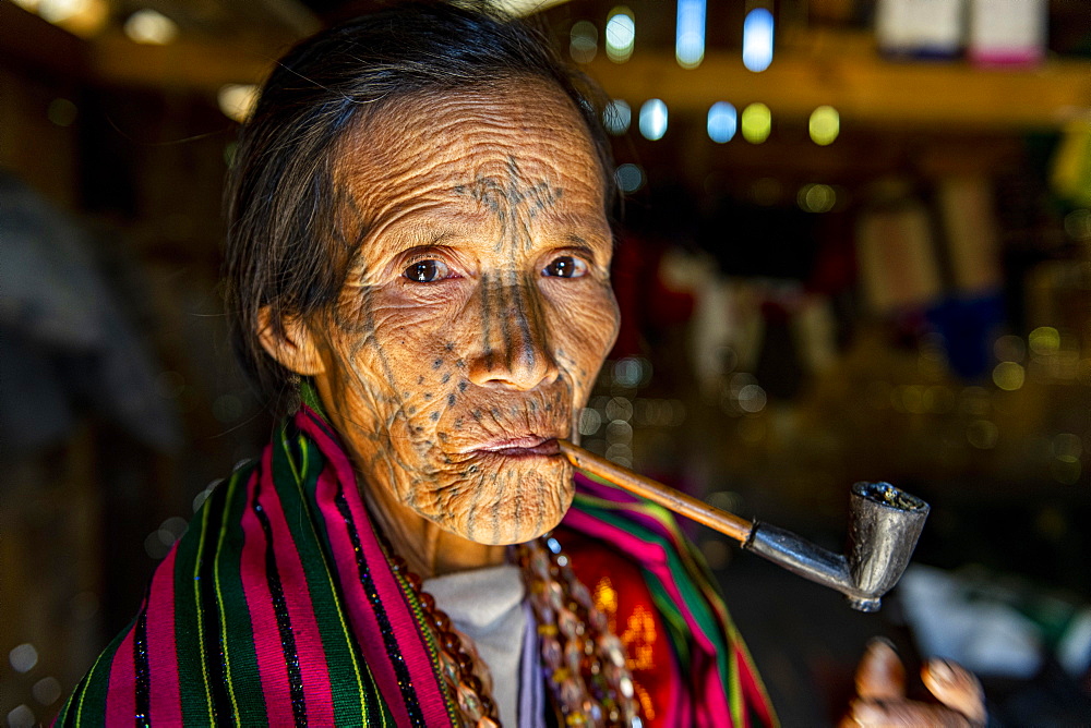 Chin woman with spiderweb tattoo smoking a pipe, Mindat, Chin state, Myanmar, Asia