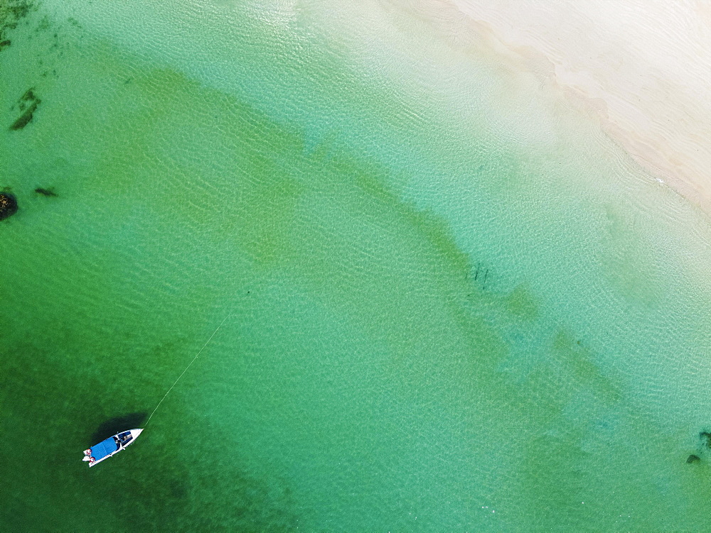 Aerial of a little boat in the clear waters anchoring on a beach on Smart island, Mergui or Myeik Archipelago, Myanmar, Asia