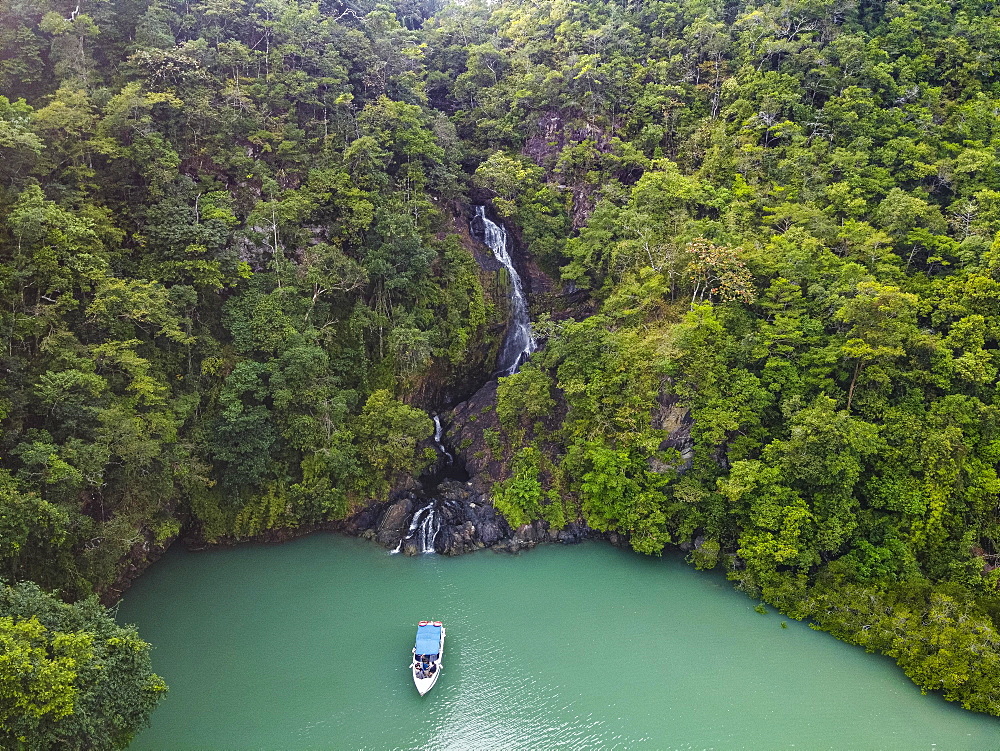 Aerial of a waterfall dropping right in the ocean on Dome island, Mergui or Myeik Archipelago, Myanmar, Asia