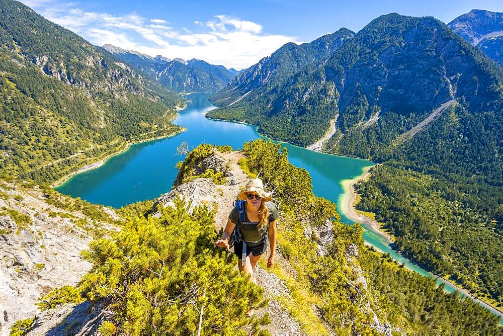 Hiker walking at Plansee, mountains with lake, Ammergau Alps, district Reutte, Tyrol, Austria, Europe