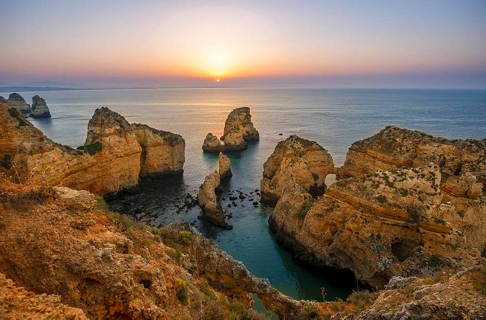 Rugged rocky coast with cliffs of sandstone, rock formations in the sea, Ponta da Piedade, dawn at sunrise, Algarve, Lagos, Portugal, Europe