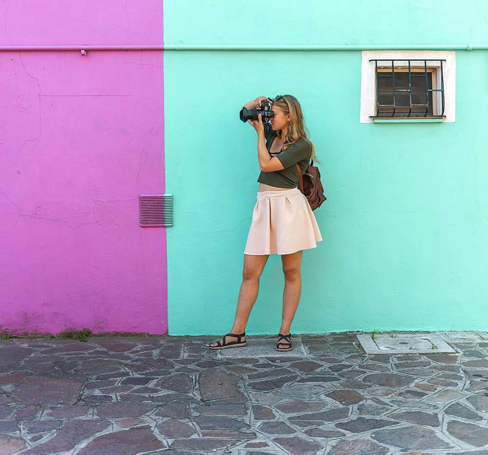 Young woman in front of colorful house, pink and turquoise house facade, tourist photographed on Burano Island, Venice, Veneto, Italy, Europe