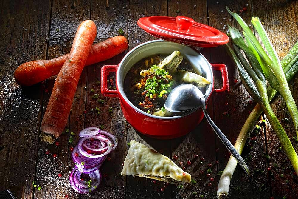 Maultaschen soup in the pot, Maultaschen in the broth, decorated with fresh vegetables