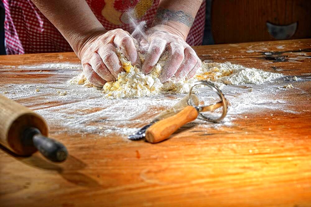 Cook kneading pasta dough on wooden table, Germany, Europe