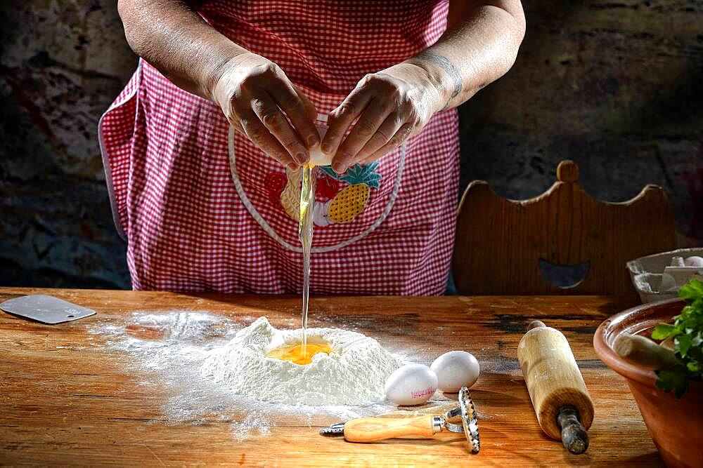 Woman beats egg on flour for pasta dough, Germany, Europe