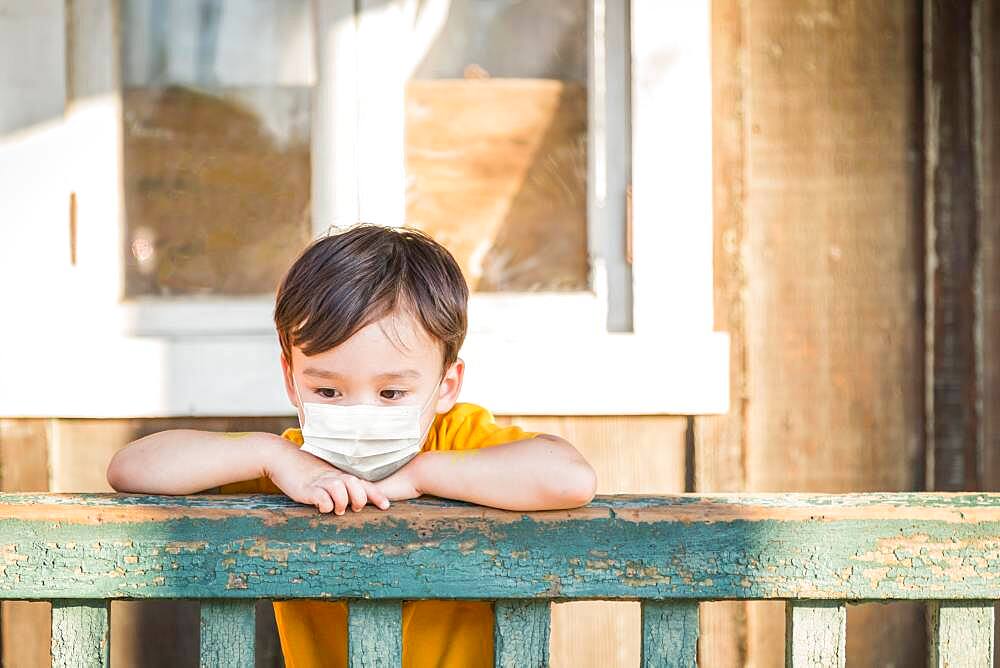 Young Mixed Race Chinese and Caucasian Boy Playing Alone Wearing Medical Face Mask Outside