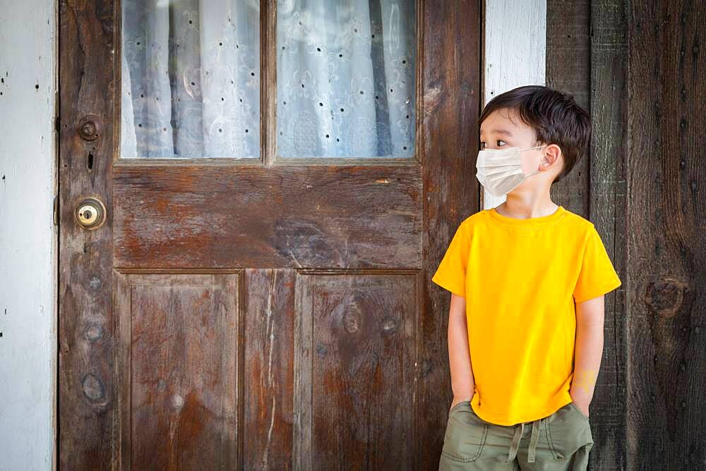 Young Mixed Race Chinese and Caucasian Boy Playing Alone Wearing Medical Face Mask Outside