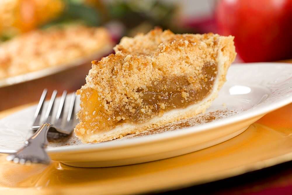 Apple pie slice with crumb topping and fork