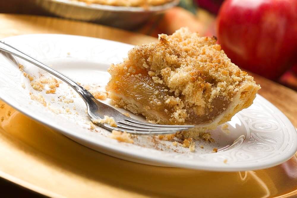 Half eaten apple pie slice with crumb topping and fork