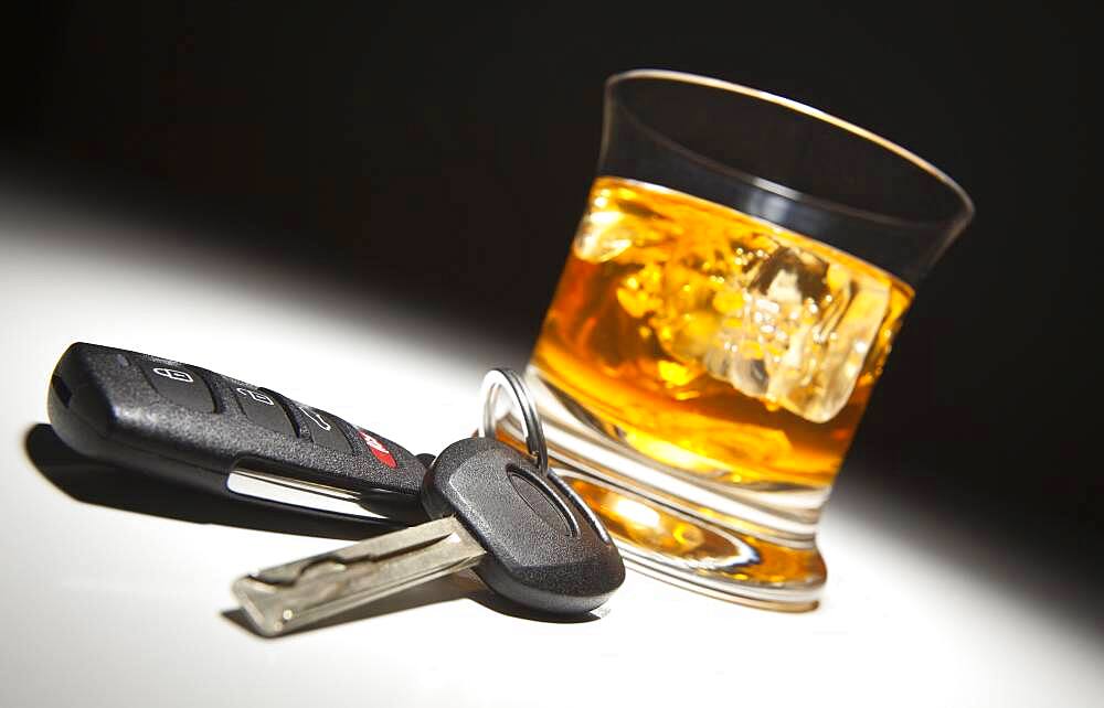 Alcoholic drink and car keys under spot light