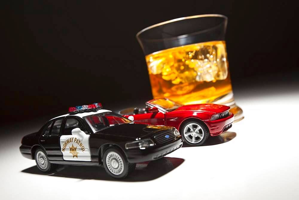 Police and sports car next to alcoholic drink under spot light