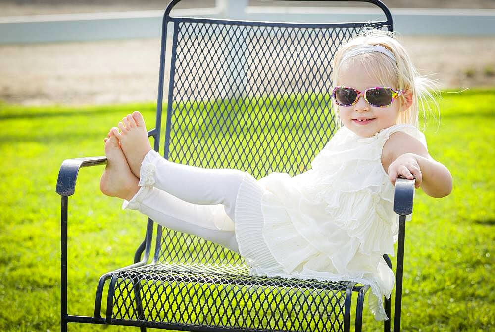 Cute playful baby girl wearing sunglasses outside at the park