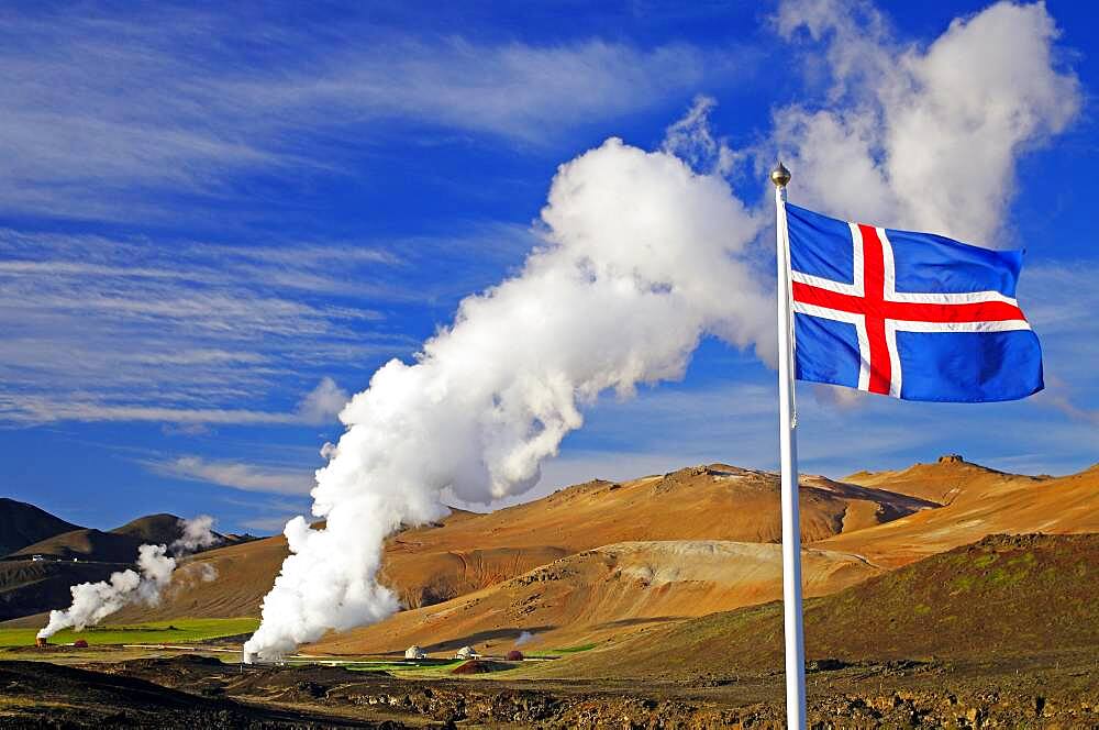 Icelandic flag in front of hot steam plumes, geothermal fields in the background, Reykjahlio, Myvatn, Iceland, Europe