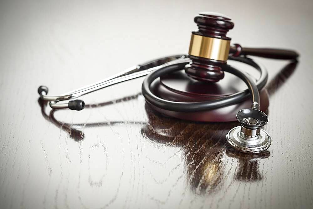 Gavel and stethoscope on reflective wooden table