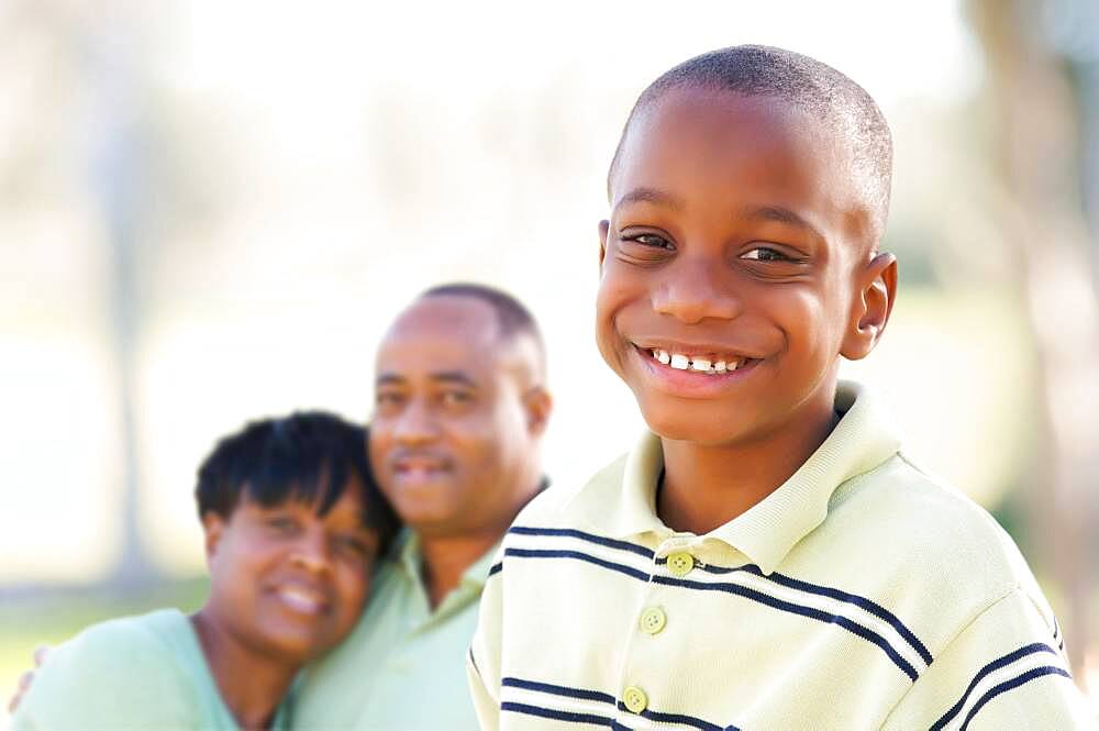 Handsome african american boy with proud parents standing by in the park