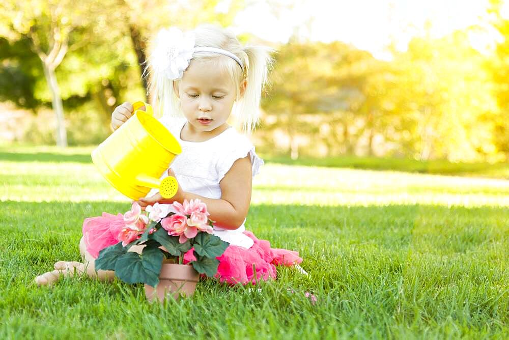 Cute little girl playing gardener with her tools and flower pot