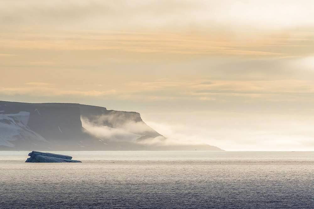 Iceberg floating before the flat table mountains covered with ice, Franz Josef Land archipelago, Russia, Europe