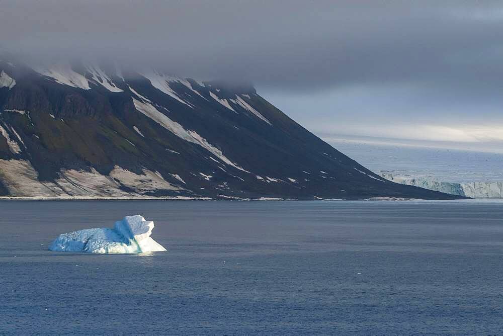 Iceberg floating before the flat table mountains covered with ice, Franz Josef Land archipelago, Russia, Europe