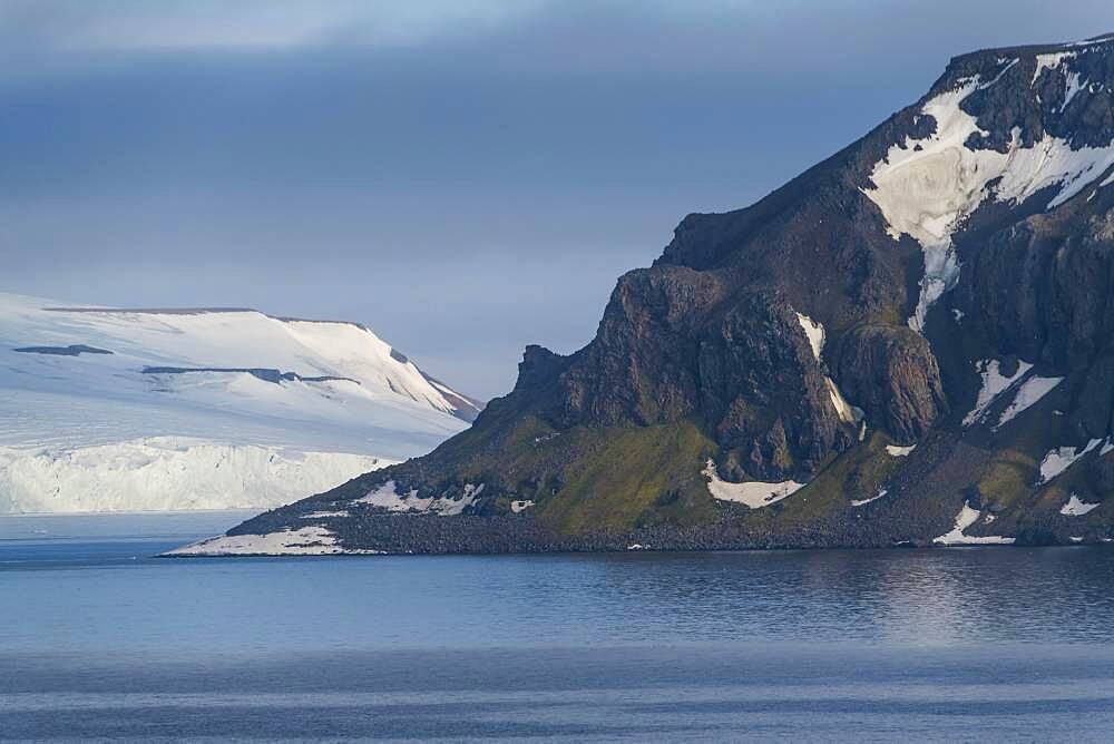 Green cliff in the glacier covered moutains of Franz Josef Land archipelago, Russia, Europe