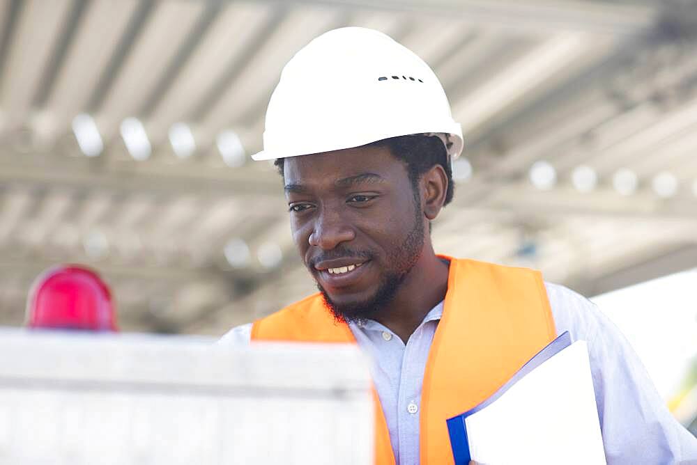 Young black man working outside as technician with helmet and safety vest, Freiburg, Baden-Wuerttemberg, Germany, Europe