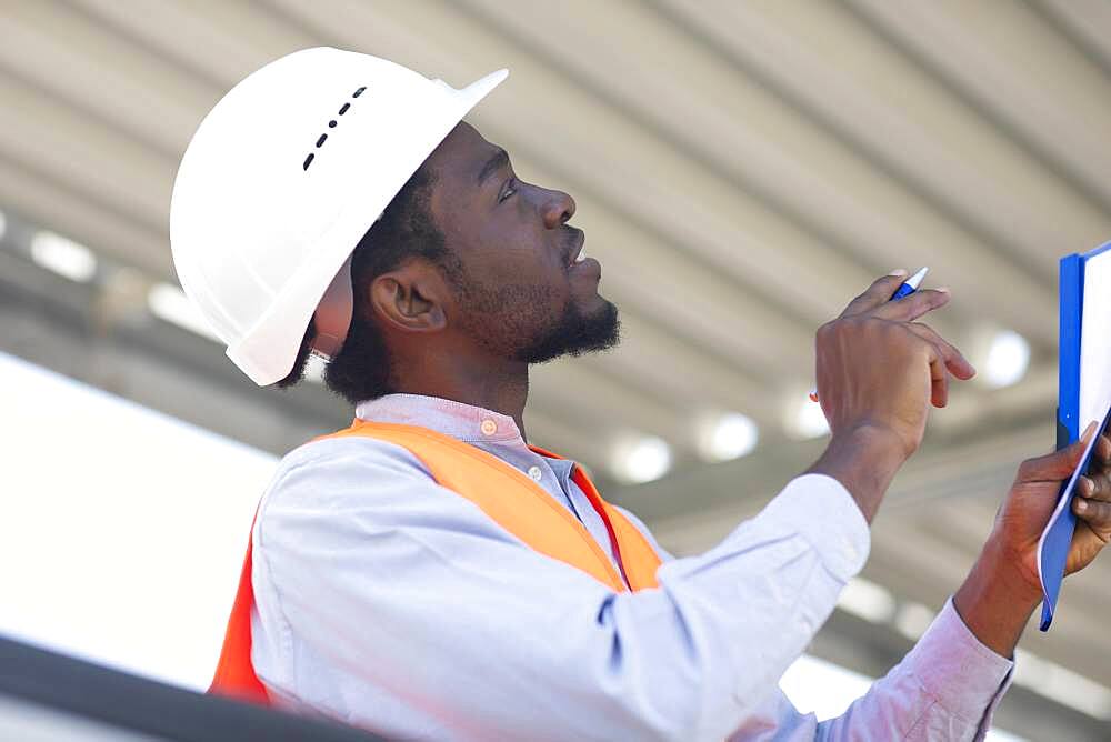 Young black man working outside as technician with helmet and safety vest, Freiburg, Baden-Wuerttemberg, Germany, Europe