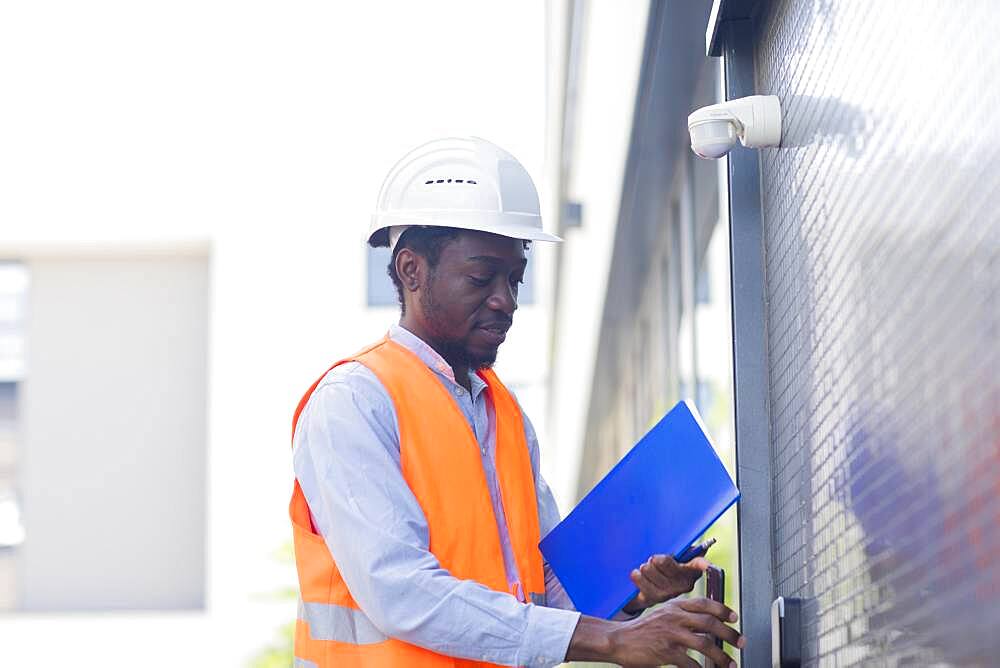 Young black man working outside as technician with helmet and safety vest, Freiburg, Baden-Wuerttemberg, Germany, Europe