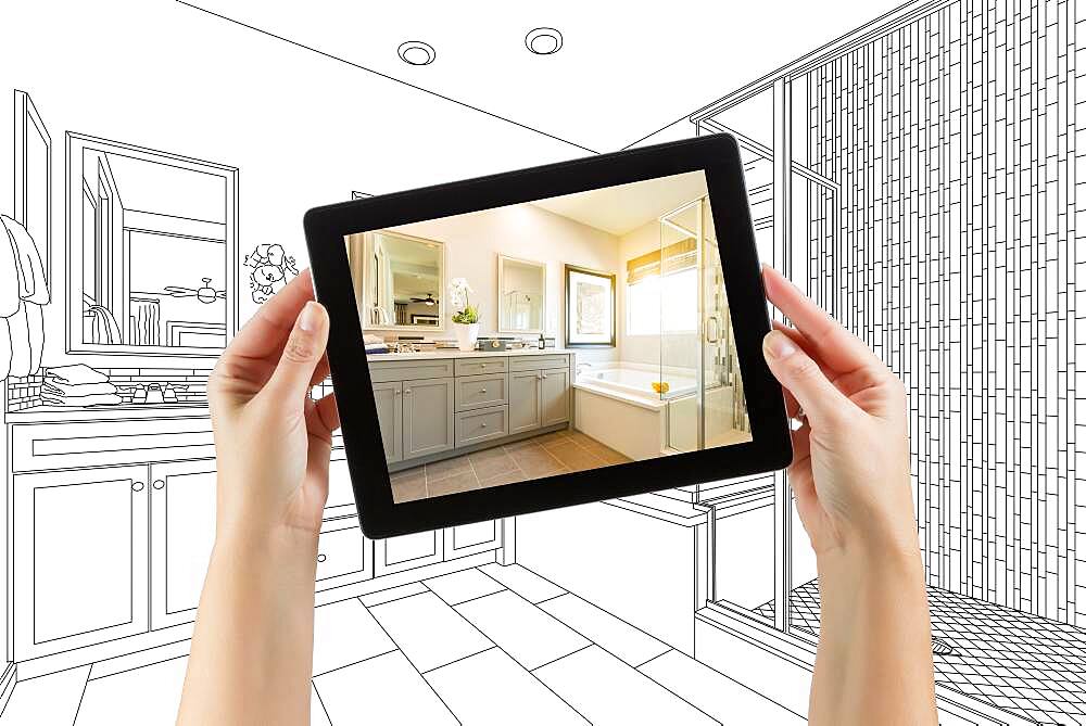 Hands holding computer tablet with master bathroom photo on screen and drawing behind