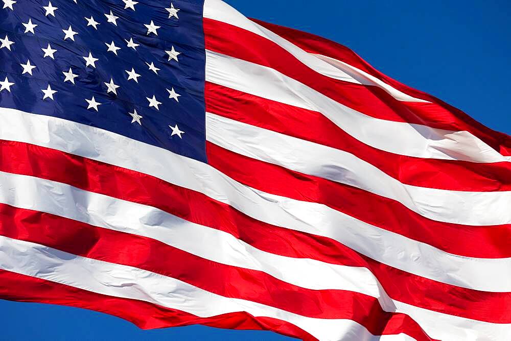 American flag waving in wind against a deep blue sky