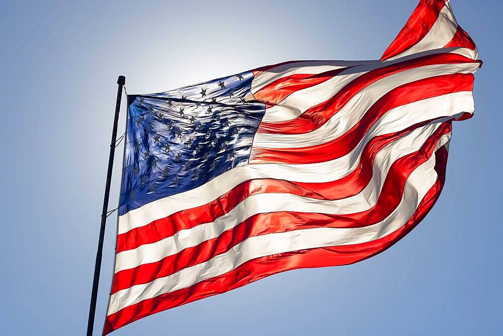 Backlit american flag waving in wind against a deep blue sky